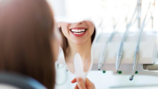 Woman looking at results of smile makeover in mirror